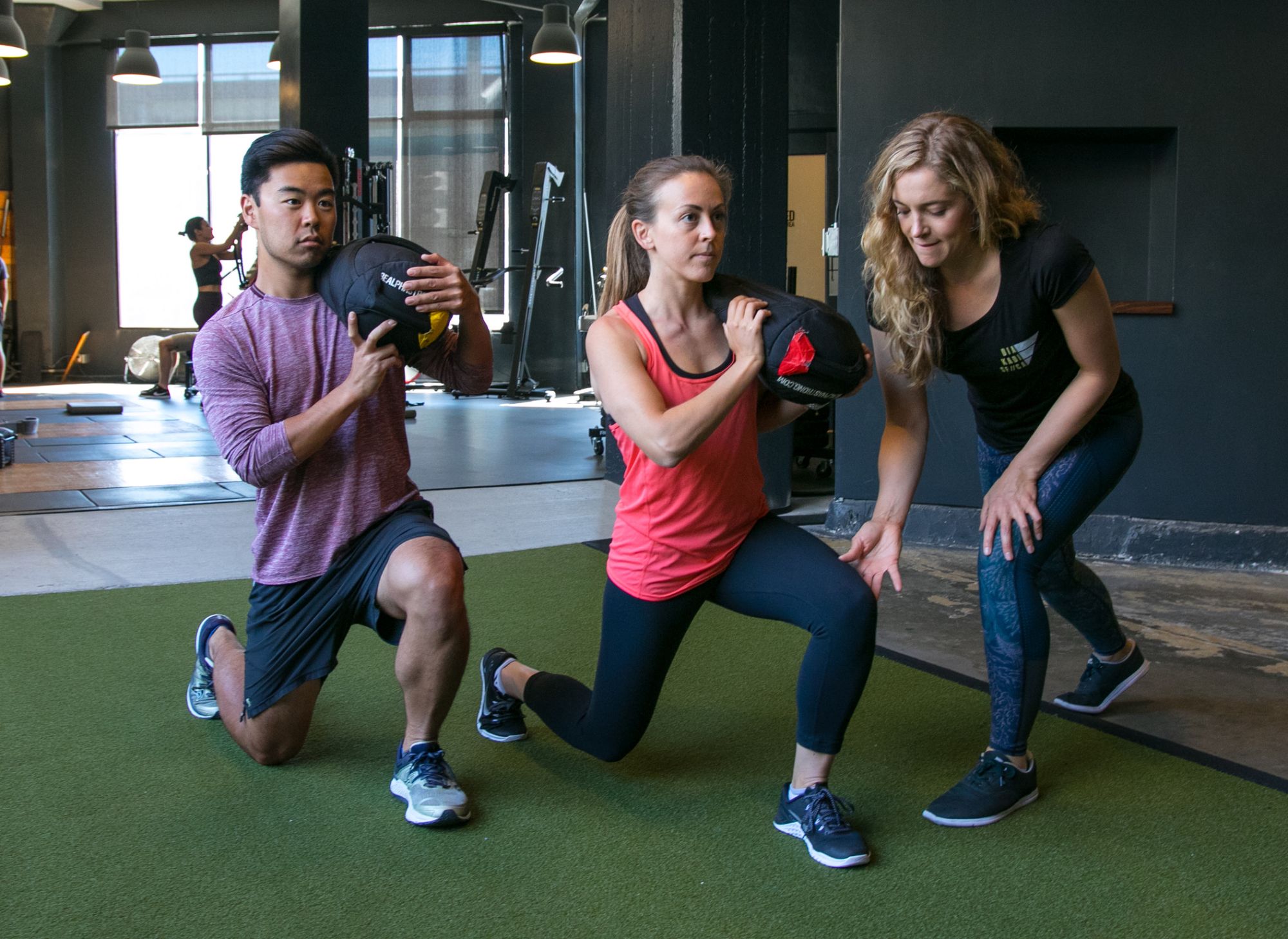 Jenna coaching two clients through a loaded lunge